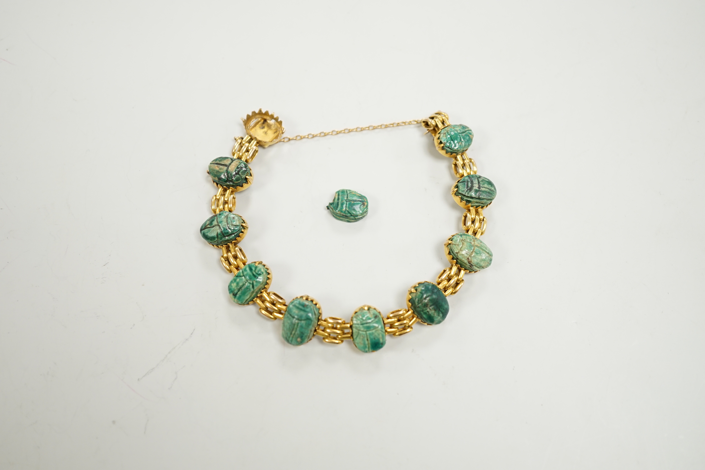 An early 20th century 9ct and ten stone ceramic scarab set bracelet (one stone loose), approx. 17cm, gross weight 20.3 grams.